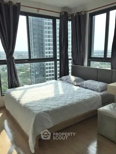 Spacious bedroom with large windows offering stunning city views in a modern high-rise apartment.