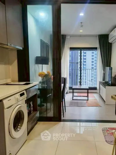 Modern apartment with open kitchen and living room, featuring a washing machine and city view balcony.