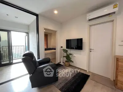 Modern living room with sleek design, featuring a comfortable recliner, wall-mounted TV, and balcony access.