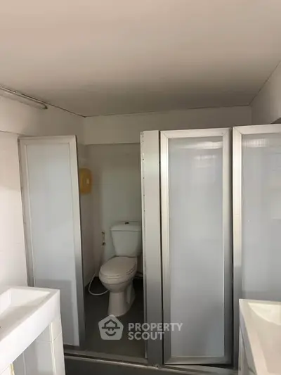 Compact bathroom with toilet and shower cubicle in modern apartment.