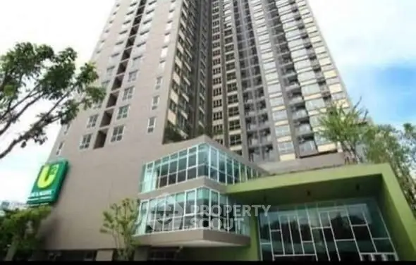 Modern high-rise building with glass facade and lush greenery, ideal for urban living.