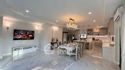 Luxurious open-plan living and dining area with elegant chandelier and modern kitchen.