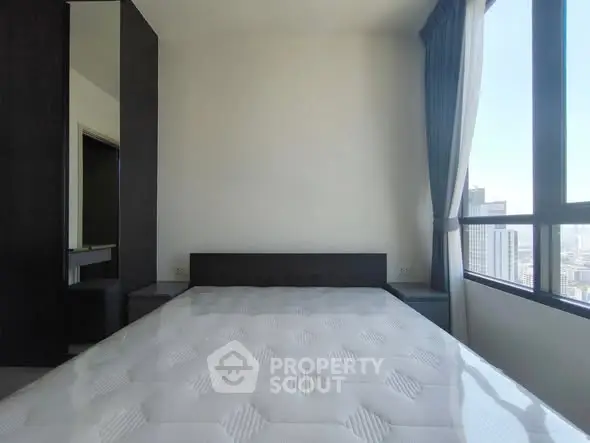 Modern bedroom with large window and city view, featuring a minimalist design and natural light.