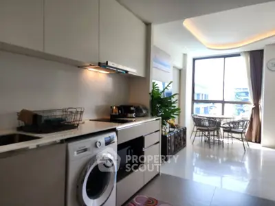 Modern kitchen with washing machine and dining area in bright apartment