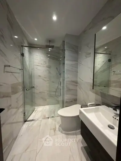 Luxurious modern bathroom with marble tiles and glass shower enclosure