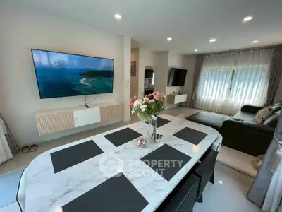 Spacious modern living room with elegant decor and large TV, perfect for relaxation and entertainment.