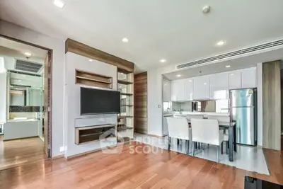 Modern open-plan living room with sleek kitchen and dining area, featuring wooden flooring and contemporary design.