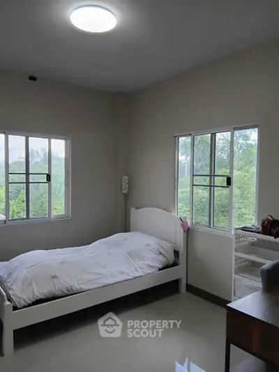 Cozy bedroom with large windows offering lush green views, perfect for relaxation and tranquility.