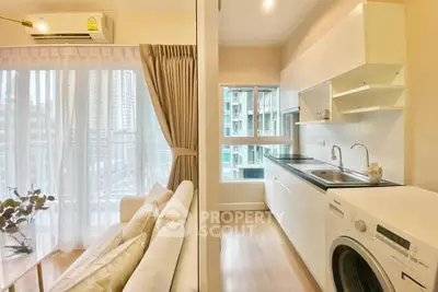 Modern apartment with open kitchen and cozy living area, featuring a washing machine and large windows.