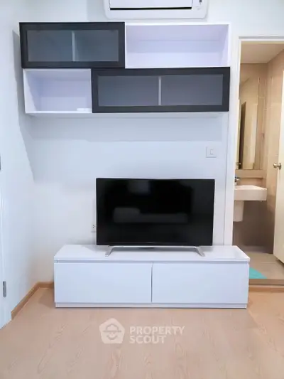 Modern living room with sleek TV stand and wall-mounted storage in a compact space.