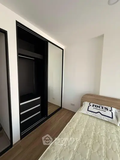 Modern bedroom with sleek black wardrobe and cozy bed in a minimalist design.