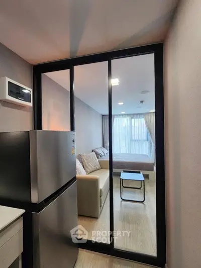 Modern apartment interior with sliding glass doors, cozy living area, and sleek kitchen appliances.