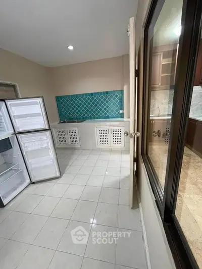 Spacious kitchen with open fridge and stylish blue tile backsplash
