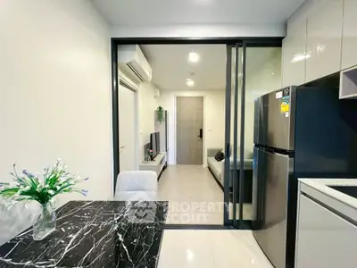 Modern apartment interior with sleek kitchen and cozy living area, featuring marble dining table and stainless steel appliances.