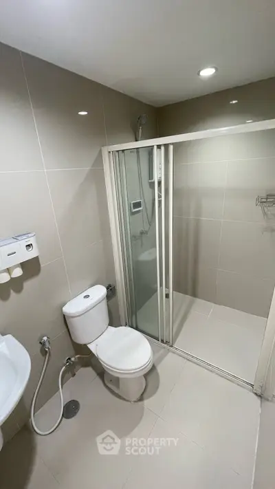 Modern bathroom with sleek shower and toilet in contemporary apartment.