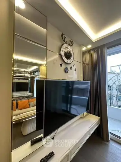 Modern living room with stylish decor and large TV, featuring elegant lighting and balcony access.
