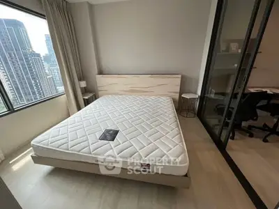 Modern bedroom with city view, featuring a comfortable bed and adjacent study area.