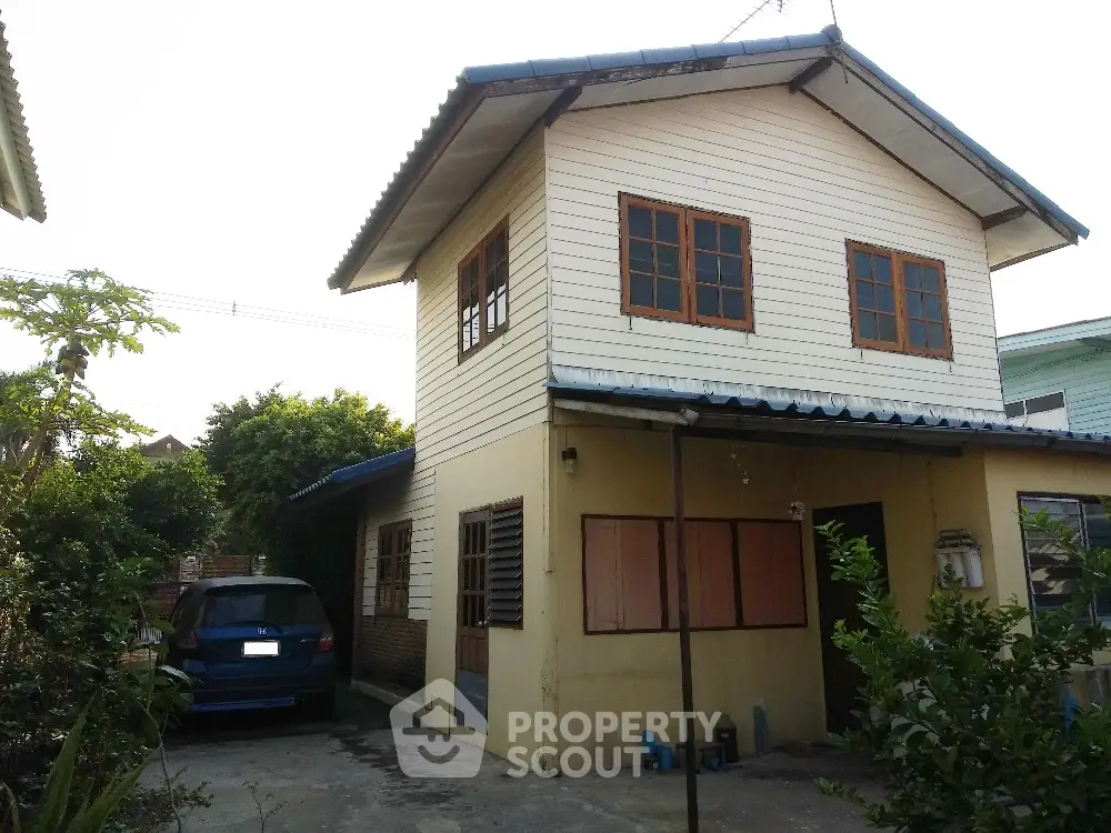 Charming two-story house with driveway and lush greenery, perfect for family living.