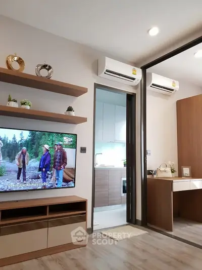 Modern living room with TV, air conditioning, and view into sleek kitchen