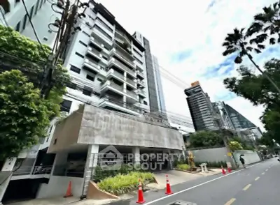 Modern urban building exterior with lush greenery and clear sky, showcasing contemporary architecture.