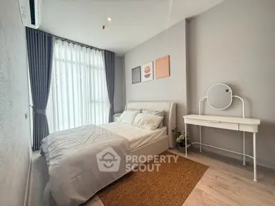 Modern bedroom with stylish decor and natural light, featuring a cozy bed and elegant vanity.