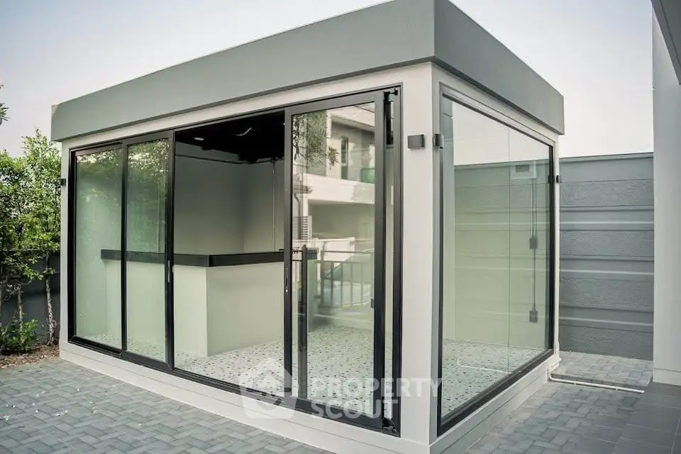Modern glass-walled exterior structure with sleek design and spacious patio area.