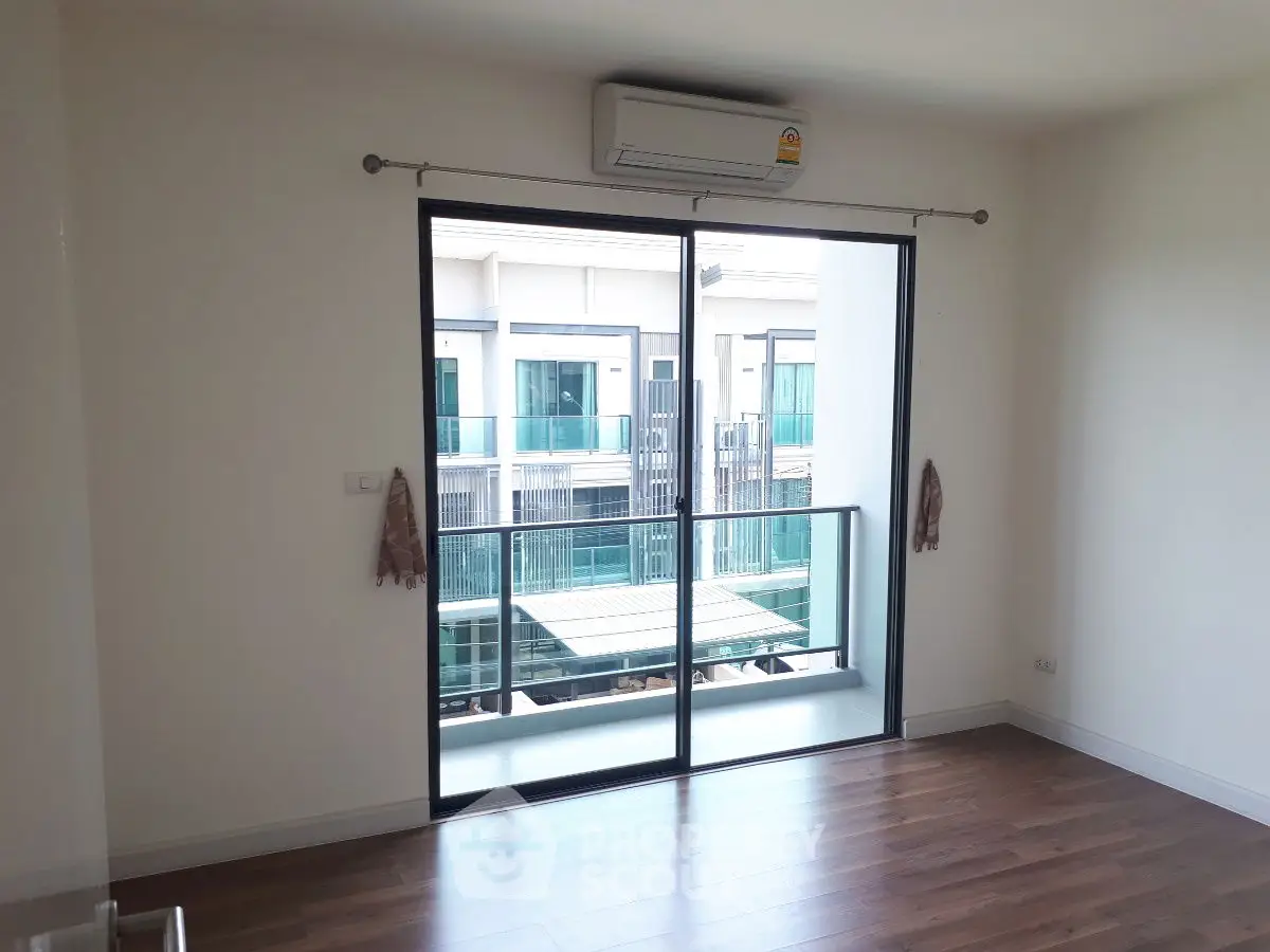 Modern apartment with balcony and large sliding glass doors, featuring sleek wooden flooring.