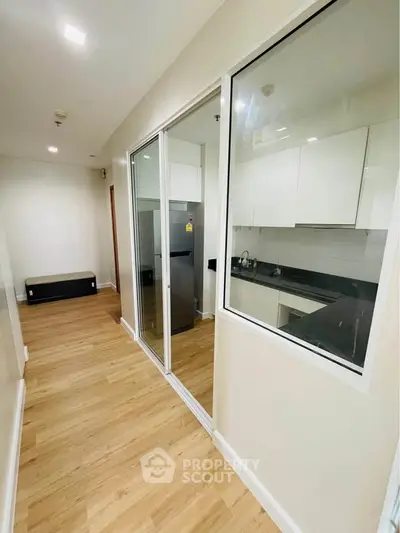 Modern apartment hallway with sleek kitchen and wooden flooring