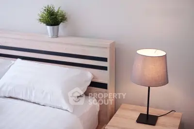 Modern bedroom with stylish wooden headboard and elegant bedside lamp.