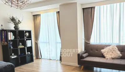 Bright living room with modern decor, large windows, and cozy seating area.