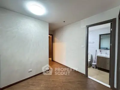 Spacious hallway leading to a modern bathroom with sleek fixtures and wooden flooring.