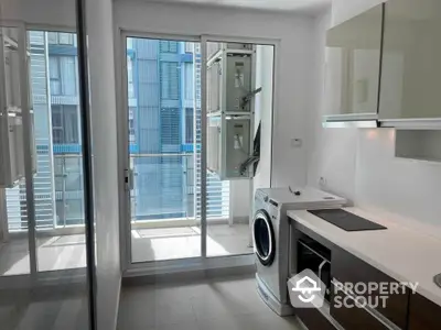 Modern kitchen with washing machine and balcony view in urban apartment