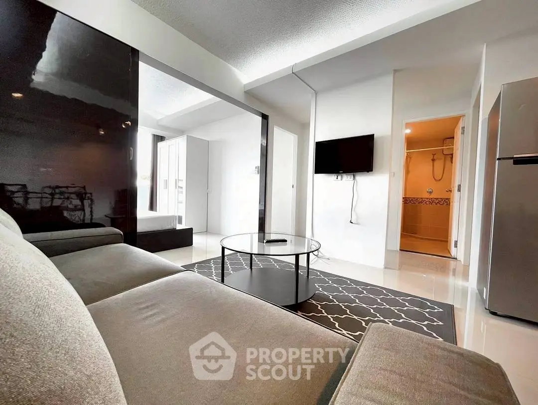 Modern living room with sleek furniture and wall-mounted TV in a bright apartment.