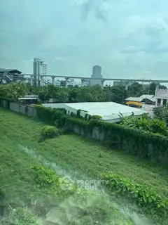 Scenic urban view with lush greenery and city skyline in the background.