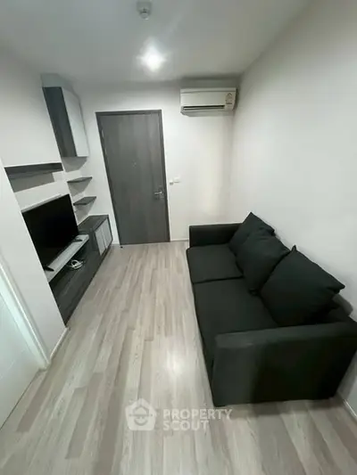 Modern living room with sleek black sofa and wall-mounted TV unit.