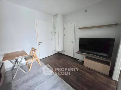 Modern living room with sleek TV setup and cozy dining area in a stylish apartment.