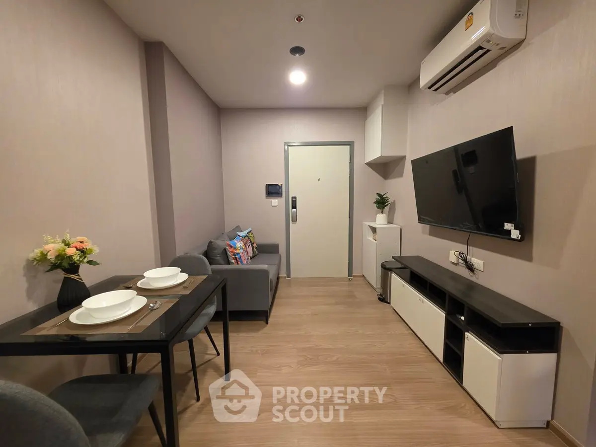 Modern living room with sleek furniture and wall-mounted TV in a cozy apartment setting.