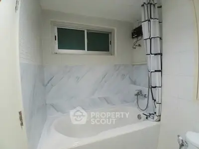 Modern bathroom with elegant marble tiles and bathtub, perfect for relaxation.