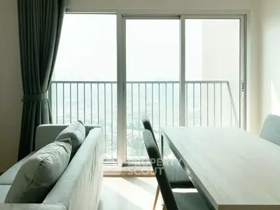 Modern living room with large window and balcony view, featuring stylish furniture and abundant natural light.