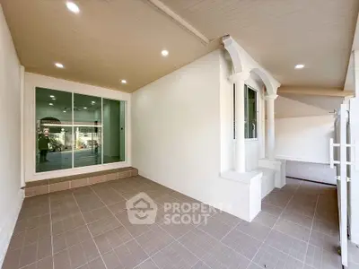 Spacious covered patio with elegant columns and tiled flooring, perfect for outdoor relaxation.