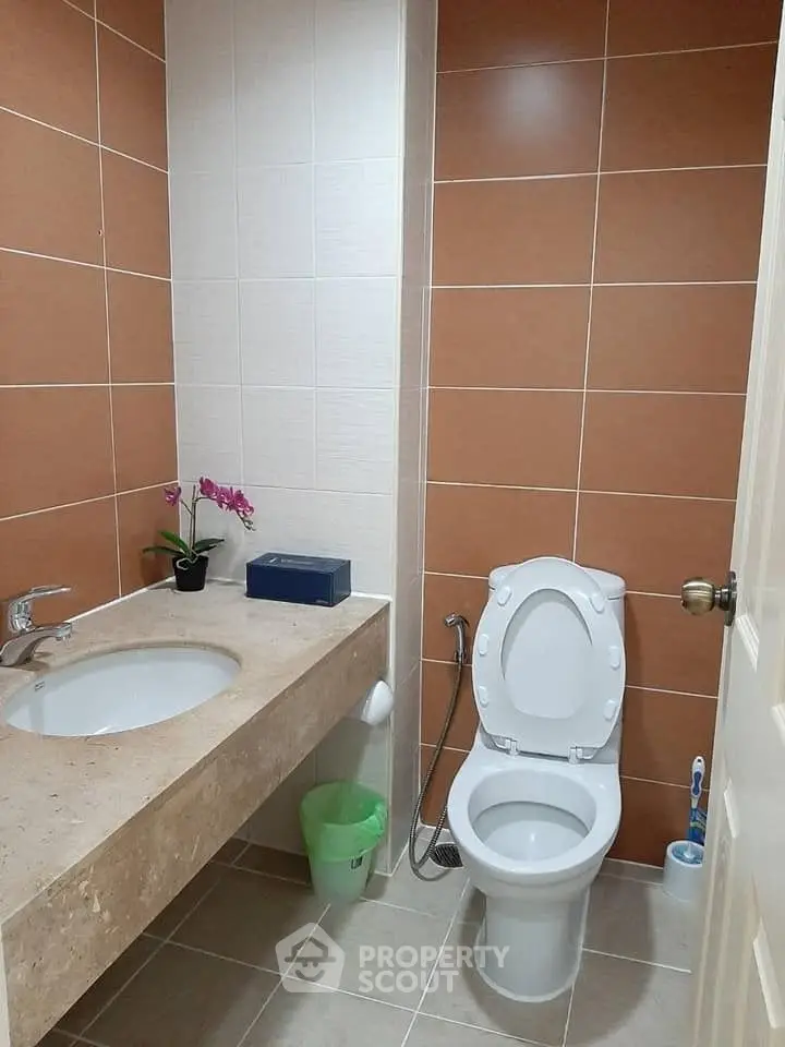 Modern bathroom with sleek fixtures and elegant tile design, featuring a spacious countertop and contemporary toilet.