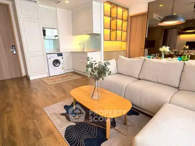 Modern living room with cozy sofa and stylish kitchen featuring washing machine.