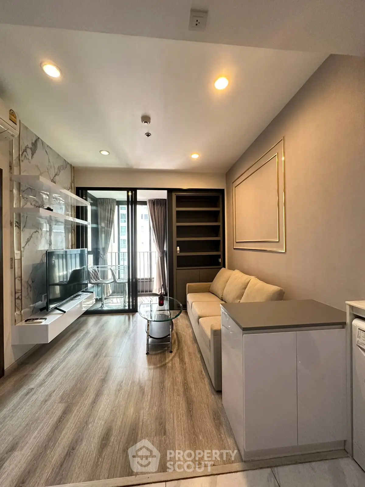 Modern living room with sleek design, featuring a cozy sofa, stylish shelving, and a balcony view.
