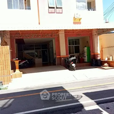 Charming residential building exterior with parking area and motorbikes, perfect for urban living.
