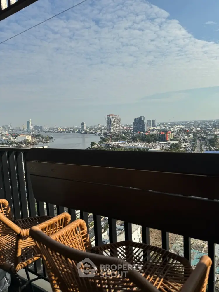 Stunning cityscape view from a high-rise balcony with modern wicker chairs.