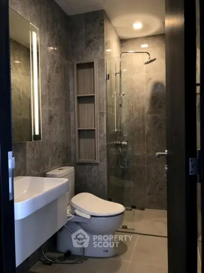 Modern bathroom with sleek design, featuring a glass shower and elegant fixtures.