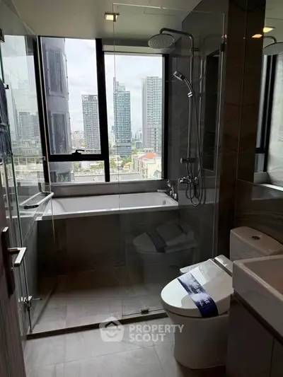 Modern bathroom with city view, featuring glass shower and bathtub in high-rise apartment.