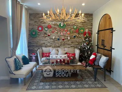 Cozy living room with festive Christmas decor, stone accent wall, and elegant chandelier.