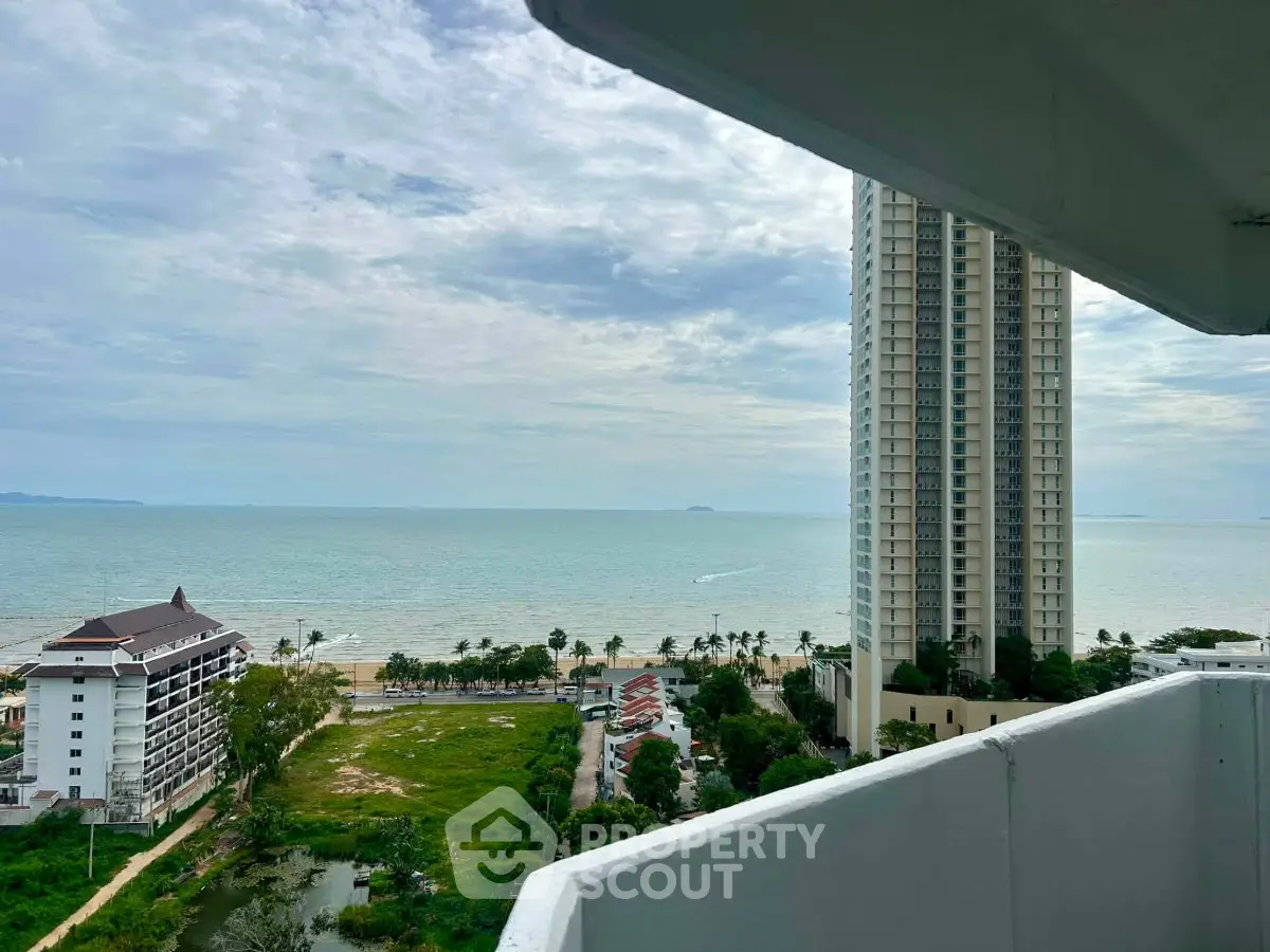 Stunning ocean view from high-rise balcony with nearby beachfront and tall buildings.