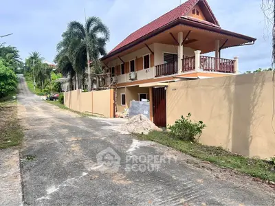 Charming two-story house with red roof and balcony on a quiet street